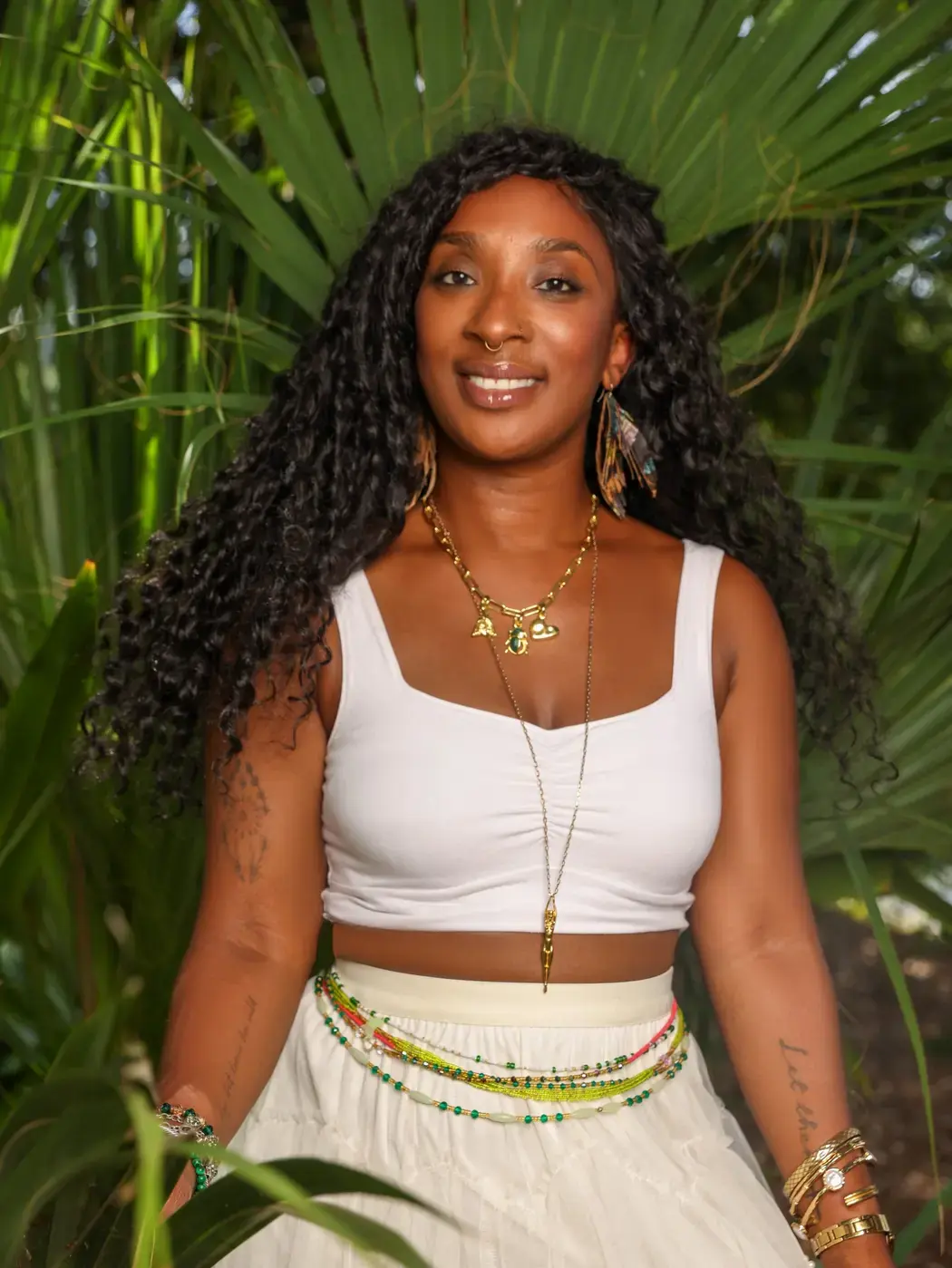 Tieara Dokes smiling among lush palm leaves